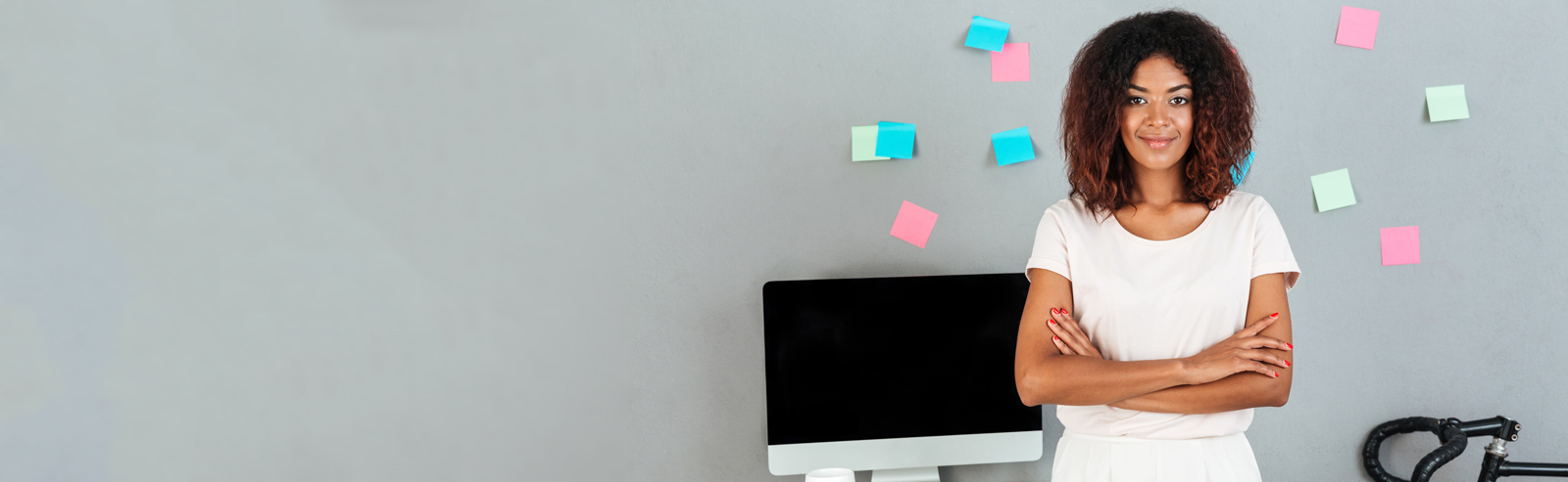 Woman smiling with grey wall behind her and multi-colored post-it notes scattered on the wall.