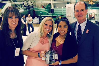 People smiling while holding an award.