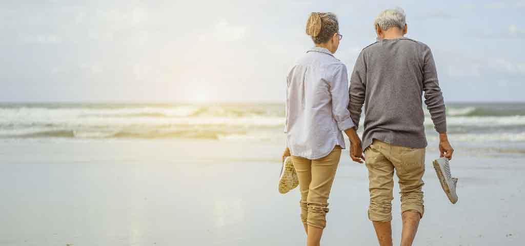 Older couple holding hands on beach